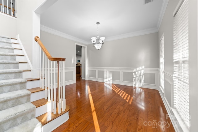 interior space featuring a chandelier, wood-type flooring, and ornamental molding