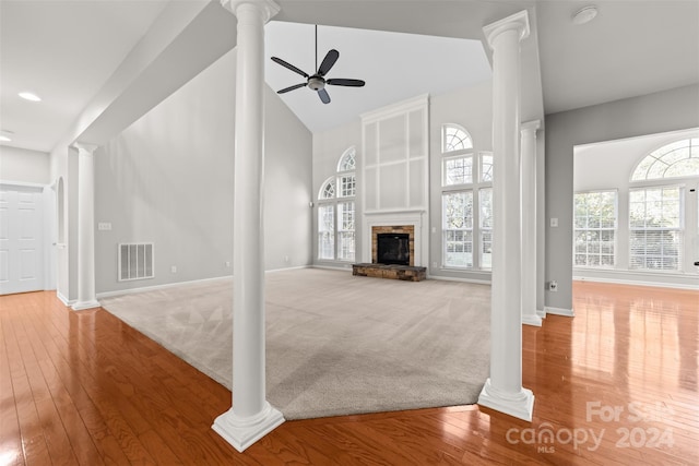 unfurnished living room featuring ornate columns, a fireplace, high vaulted ceiling, light colored carpet, and ceiling fan