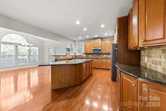 kitchen with decorative backsplash, plenty of natural light, light wood-type flooring, and appliances with stainless steel finishes