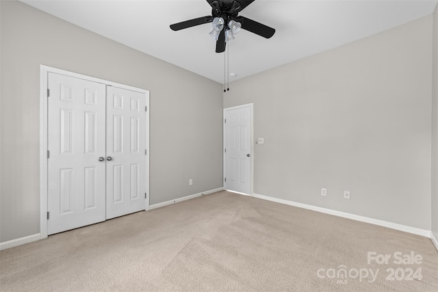 unfurnished bedroom featuring a closet, ceiling fan, and light carpet