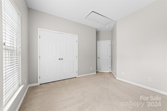 unfurnished bedroom with multiple windows, light carpet, and a closet