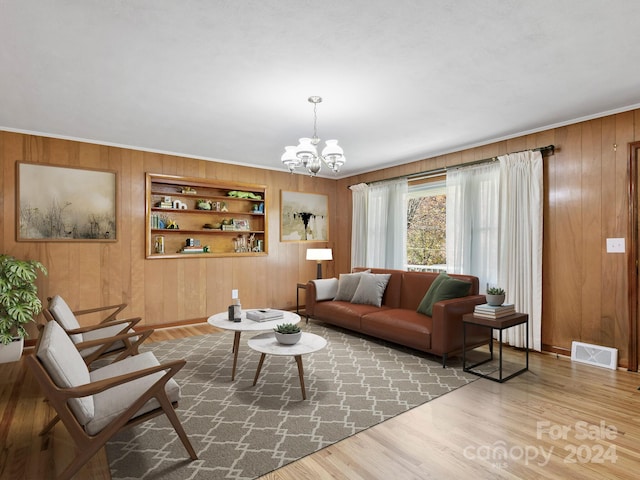 living room with wood walls, built in features, wood-type flooring, and an inviting chandelier