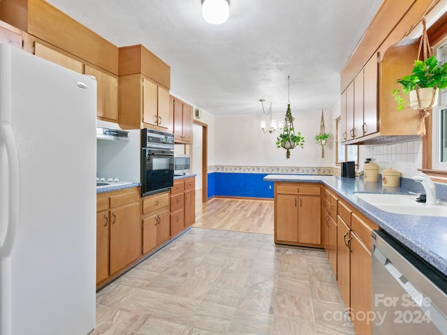 kitchen with kitchen peninsula, appliances with stainless steel finishes, light wood-type flooring, decorative light fixtures, and an inviting chandelier