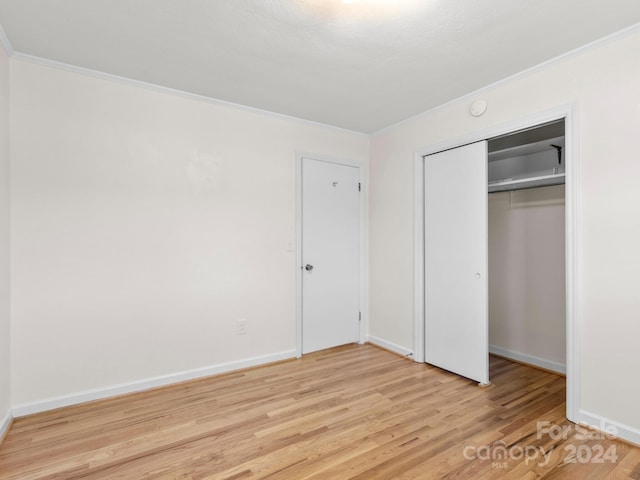 unfurnished bedroom featuring light hardwood / wood-style floors, ornamental molding, and a closet