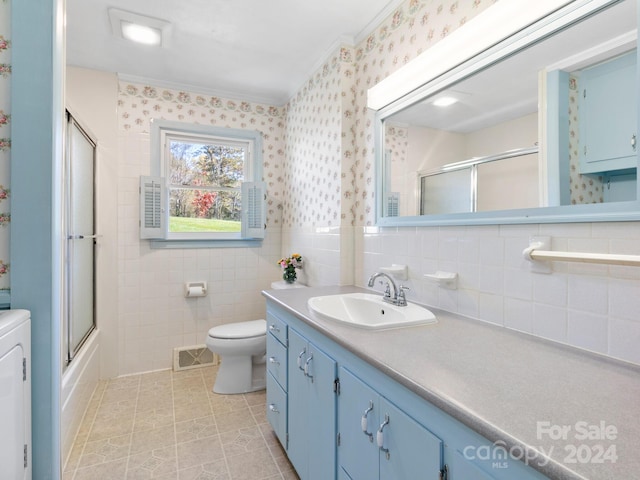 full bathroom with vanity, combined bath / shower with glass door, tile patterned flooring, toilet, and tile walls