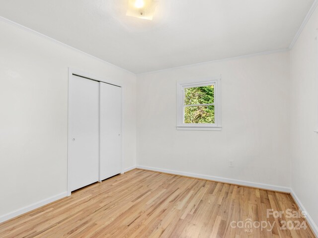 unfurnished bedroom featuring light hardwood / wood-style floors, a closet, and crown molding