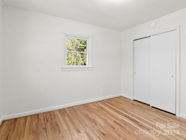 unfurnished bedroom with light hardwood / wood-style floors, a closet, and ornamental molding