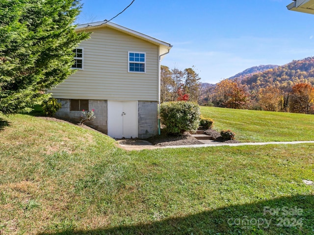 view of side of home featuring a mountain view and a lawn