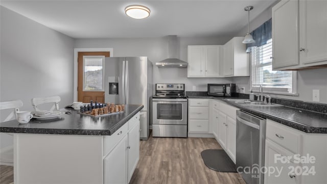 kitchen featuring wall chimney exhaust hood, white cabinetry, sink, and appliances with stainless steel finishes