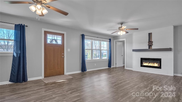 unfurnished living room featuring ceiling fan and dark wood-type flooring