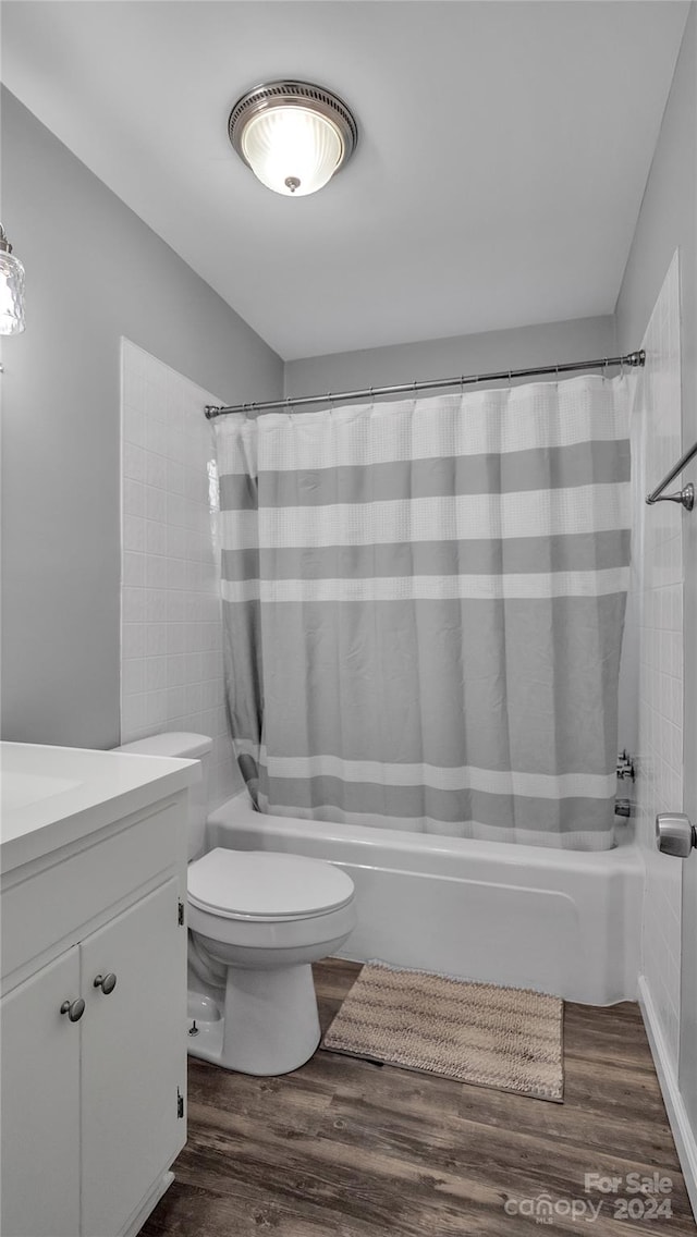 full bathroom featuring shower / bath combo with shower curtain, hardwood / wood-style floors, vanity, and toilet