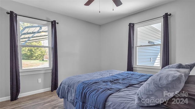 bedroom with wood-type flooring, multiple windows, and ceiling fan