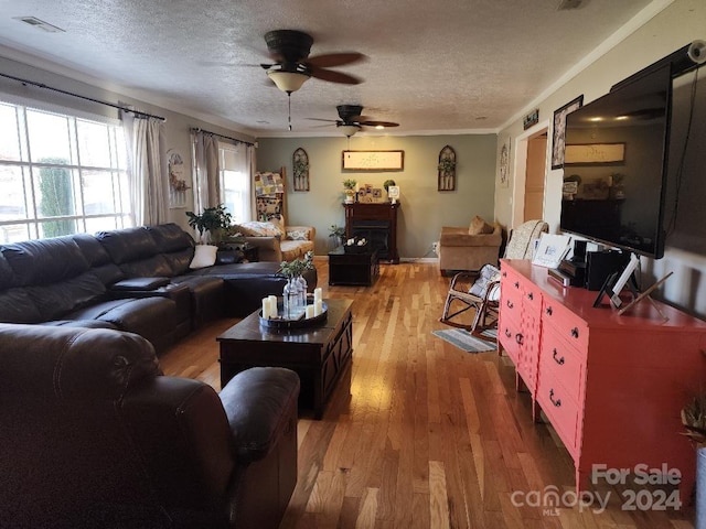 living room with hardwood / wood-style floors, ceiling fan, crown molding, and a textured ceiling