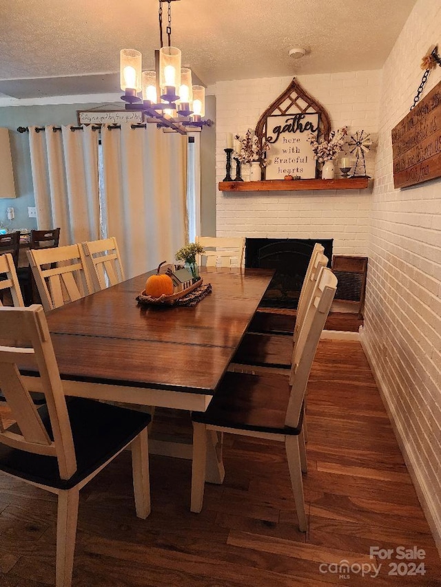 dining room with dark wood-type flooring, brick wall, and a textured ceiling