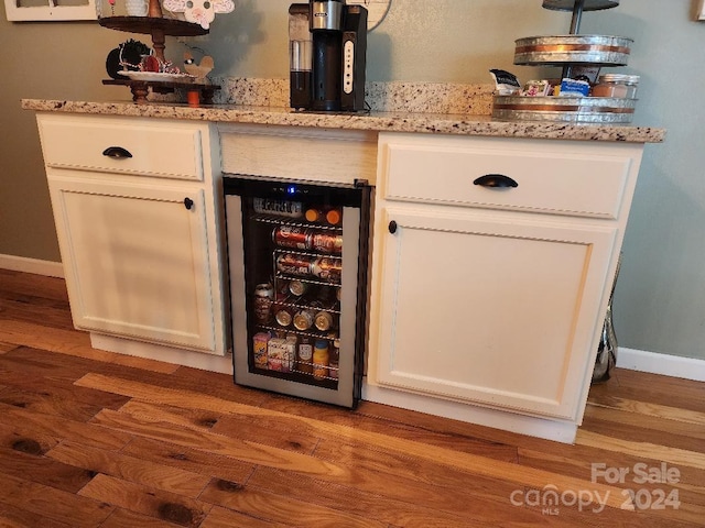 bar featuring white cabinetry, wine cooler, light stone counters, and light hardwood / wood-style floors