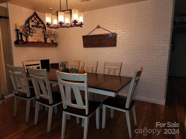 dining area with a chandelier, dark hardwood / wood-style flooring, and brick wall