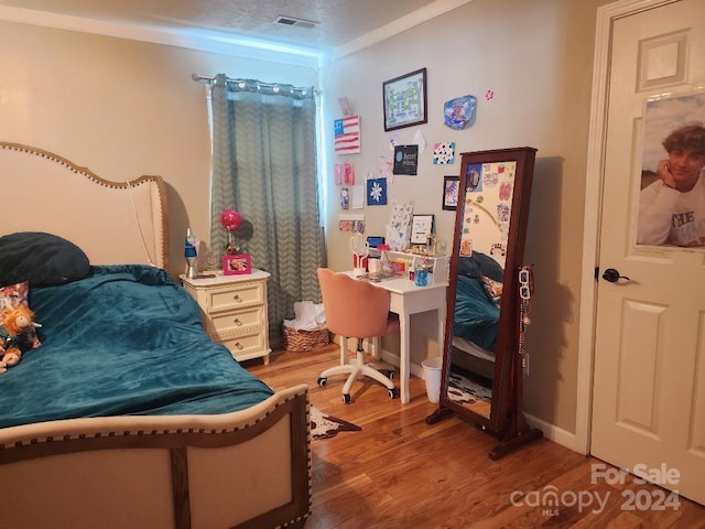 bedroom featuring hardwood / wood-style floors, a textured ceiling, and ornamental molding