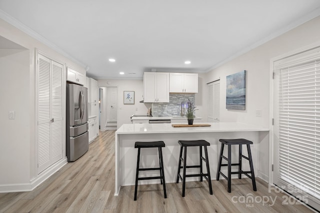 kitchen with white cabinetry, a breakfast bar area, backsplash, kitchen peninsula, and stainless steel refrigerator with ice dispenser