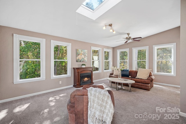 carpeted living room with ceiling fan, lofted ceiling with skylight, and a wealth of natural light