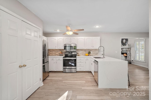 kitchen with sink, appliances with stainless steel finishes, backsplash, white cabinets, and kitchen peninsula