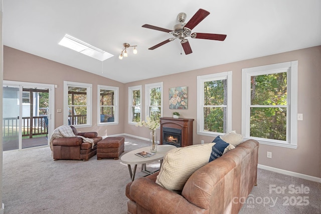 carpeted living room featuring ceiling fan and vaulted ceiling with skylight