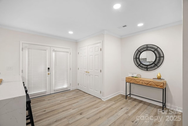 entryway featuring ornamental molding, light hardwood / wood-style floors, and french doors