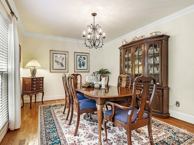 dining area with crown molding, light hardwood / wood-style flooring, and an inviting chandelier