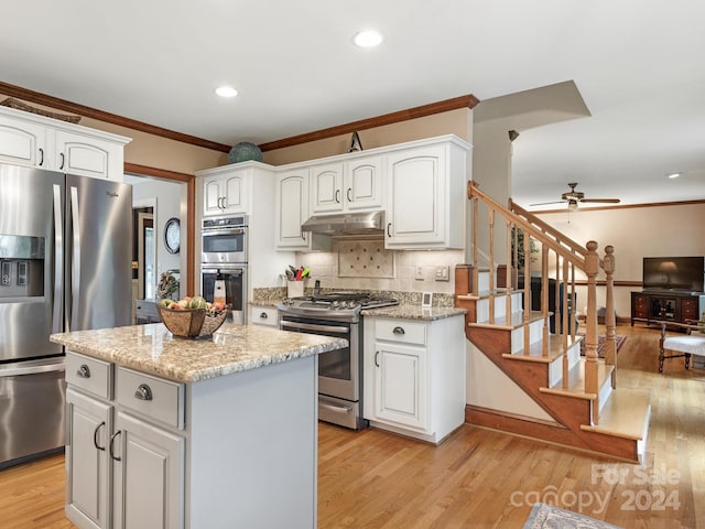 kitchen with white cabinetry, light stone counters, stainless steel appliances, and light wood-type flooring