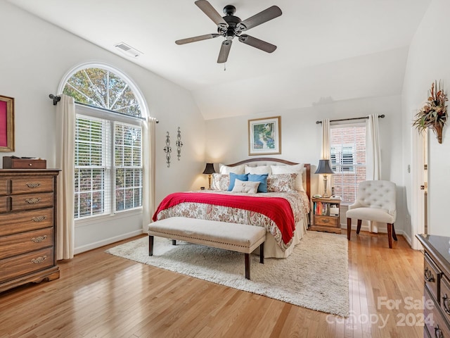 bedroom featuring vaulted ceiling, multiple windows, light wood-type flooring, and ceiling fan