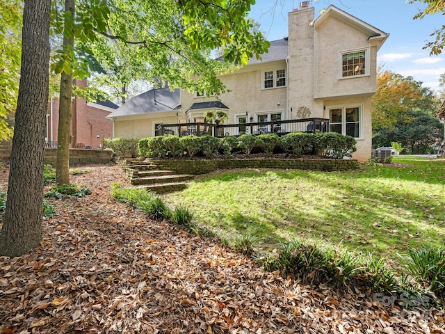 rear view of house with central AC, a deck, and a lawn