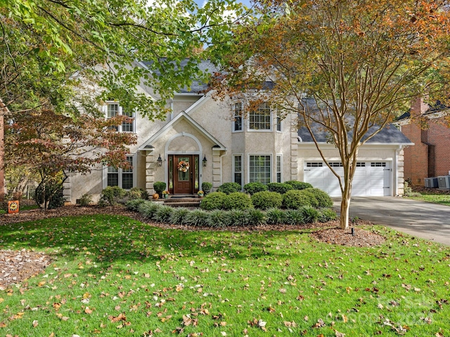 front facade with central AC, a front yard, and a garage