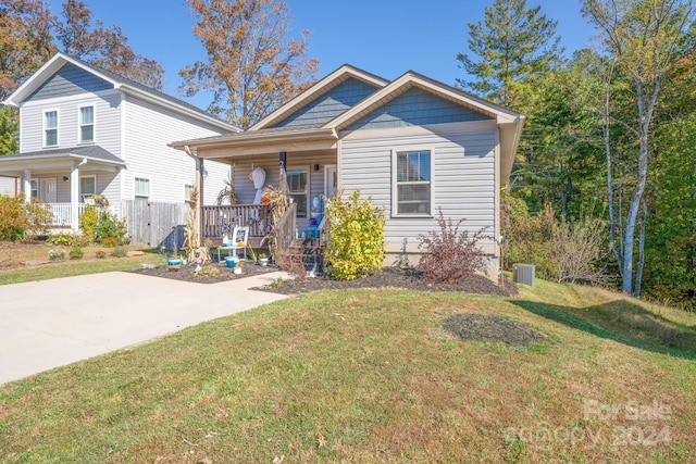 view of front facade with a front yard, a porch, and cooling unit