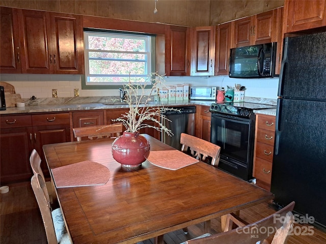 kitchen featuring light stone countertops, decorative backsplash, sink, and black appliances