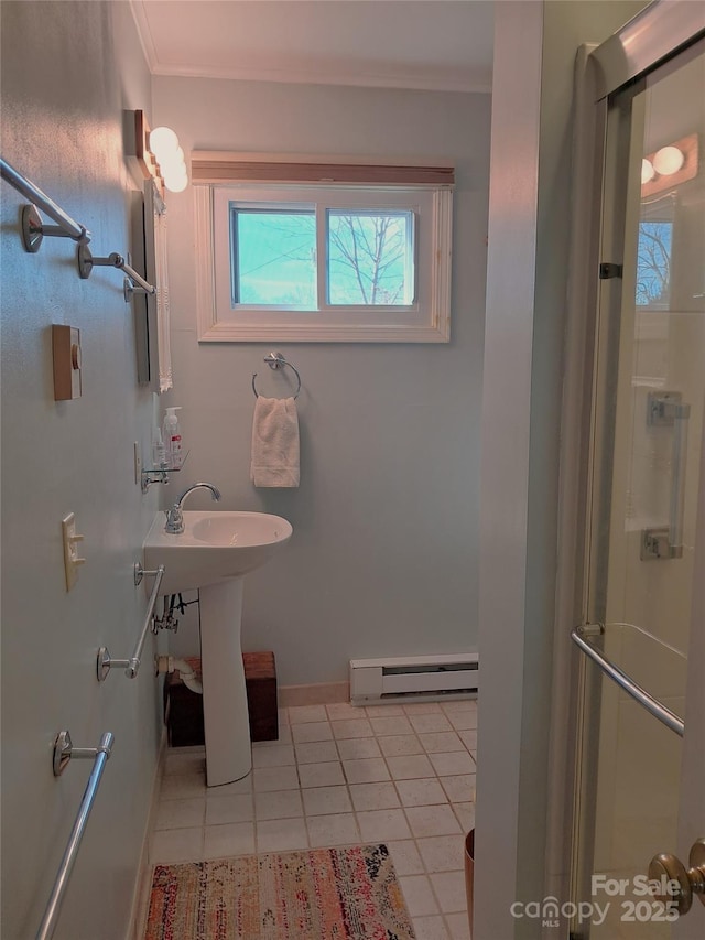 bathroom featuring a shower with door, a baseboard heating unit, tile patterned floors, crown molding, and sink