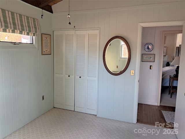 unfurnished bedroom with a closet, vaulted ceiling, and wooden walls