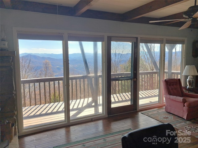 sunroom / solarium with beam ceiling, a healthy amount of sunlight, and a mountain view