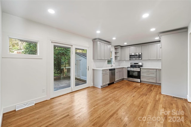 kitchen with gray cabinets, appliances with stainless steel finishes, and light hardwood / wood-style flooring