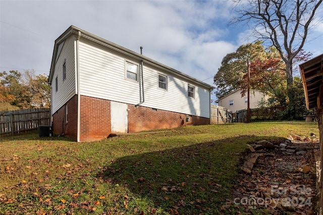 view of side of home with fence, central air condition unit, a lawn, and brick siding