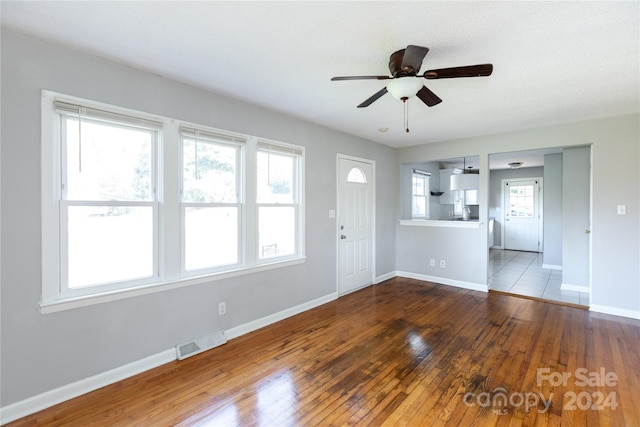 unfurnished living room with baseboards, wood-type flooring, a ceiling fan, and visible vents