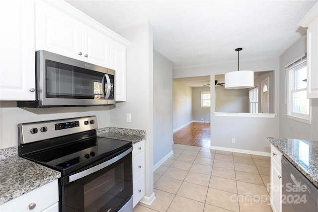 kitchen with stainless steel appliances, light stone countertops, pendant lighting, light tile patterned floors, and white cabinets