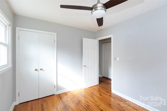 unfurnished bedroom with multiple windows, a closet, light wood-type flooring, and ceiling fan