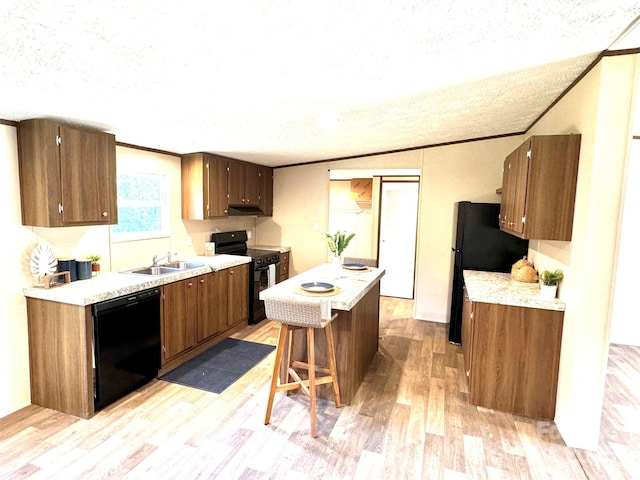 kitchen featuring black appliances, sink, a textured ceiling, light hardwood / wood-style floors, and a kitchen bar