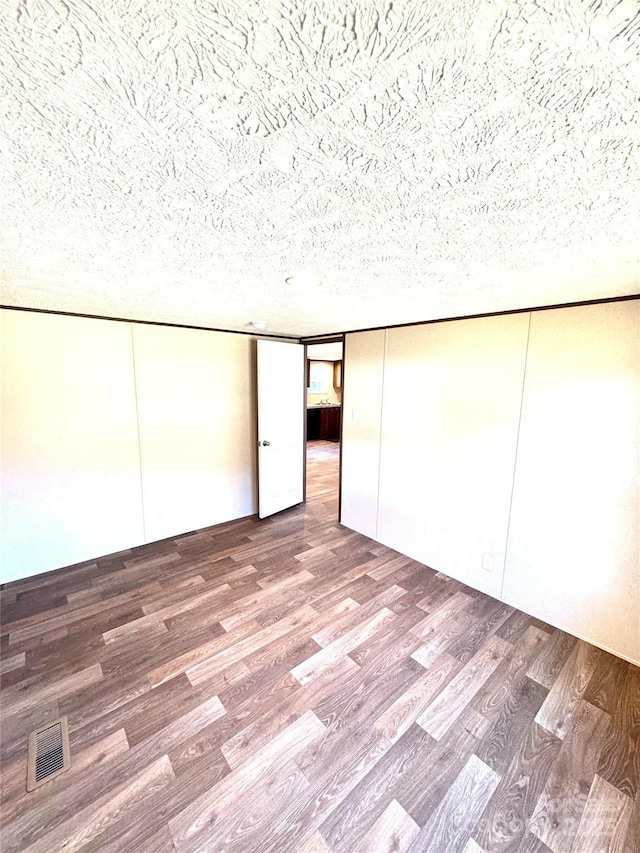 unfurnished bedroom featuring hardwood / wood-style floors, a textured ceiling, and a closet