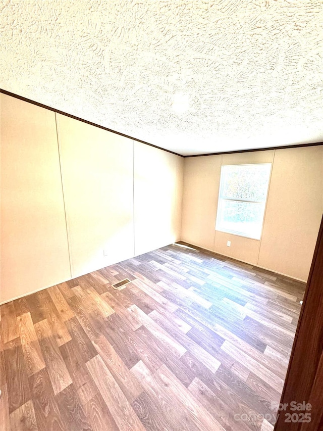 empty room with hardwood / wood-style floors and a textured ceiling