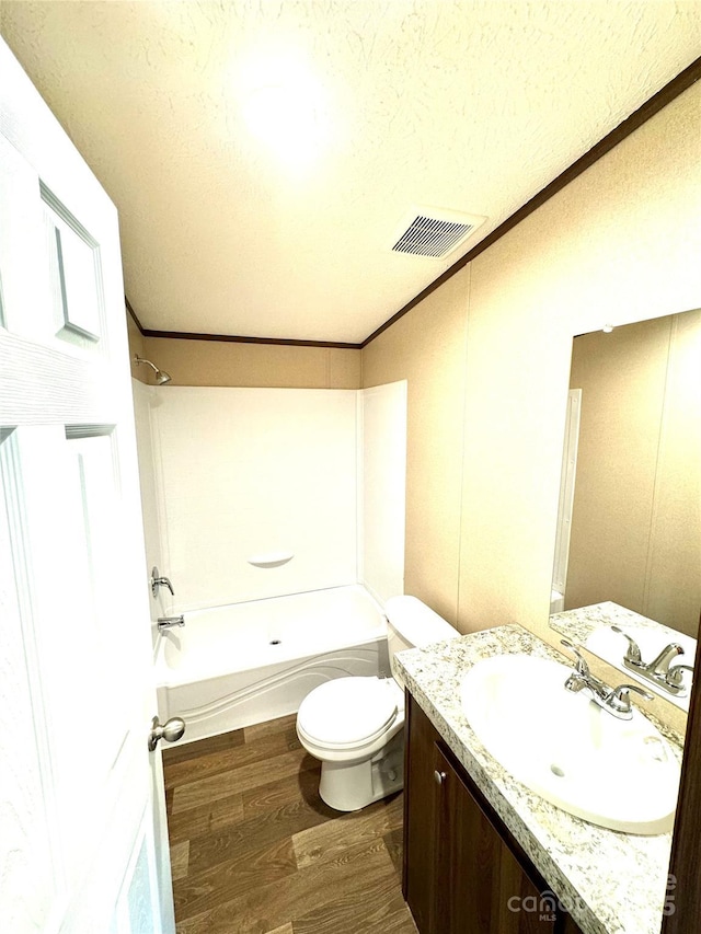 full bathroom featuring tub / shower combination, ornamental molding, a textured ceiling, wood-type flooring, and toilet