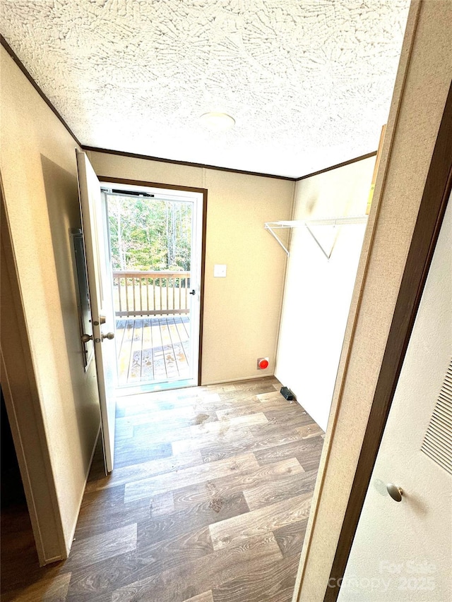 interior space featuring crown molding, wood-type flooring, and a textured ceiling