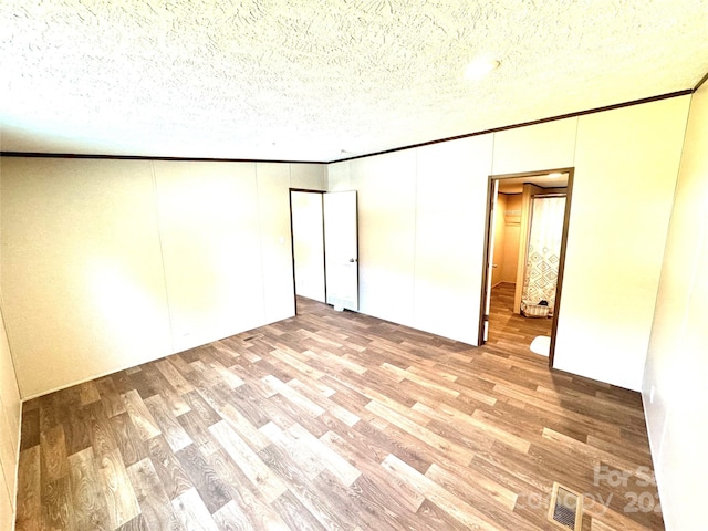 empty room featuring a textured ceiling and light hardwood / wood-style flooring