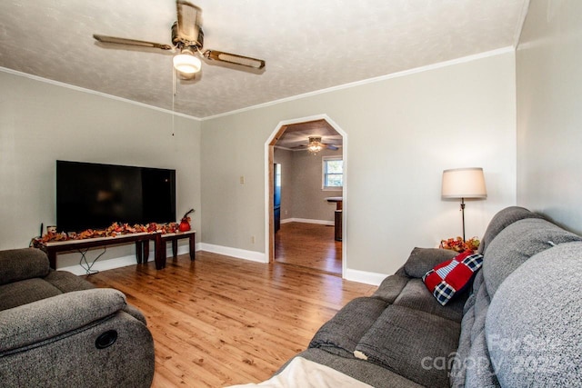 living room with a textured ceiling, hardwood / wood-style flooring, ceiling fan, and ornamental molding