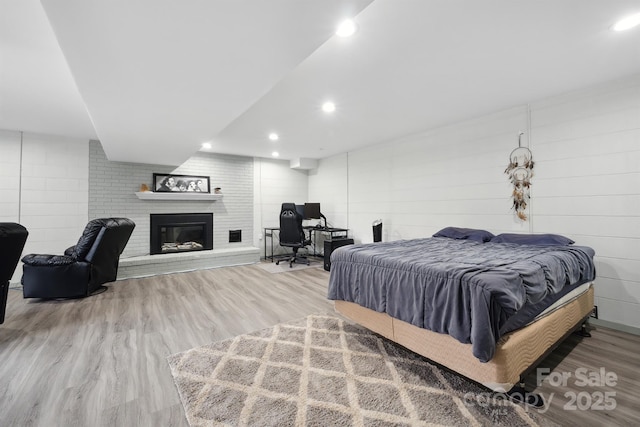 bedroom with wood-type flooring and a brick fireplace