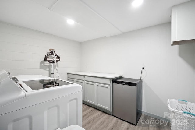 laundry area featuring cabinets, light wood-type flooring, and separate washer and dryer